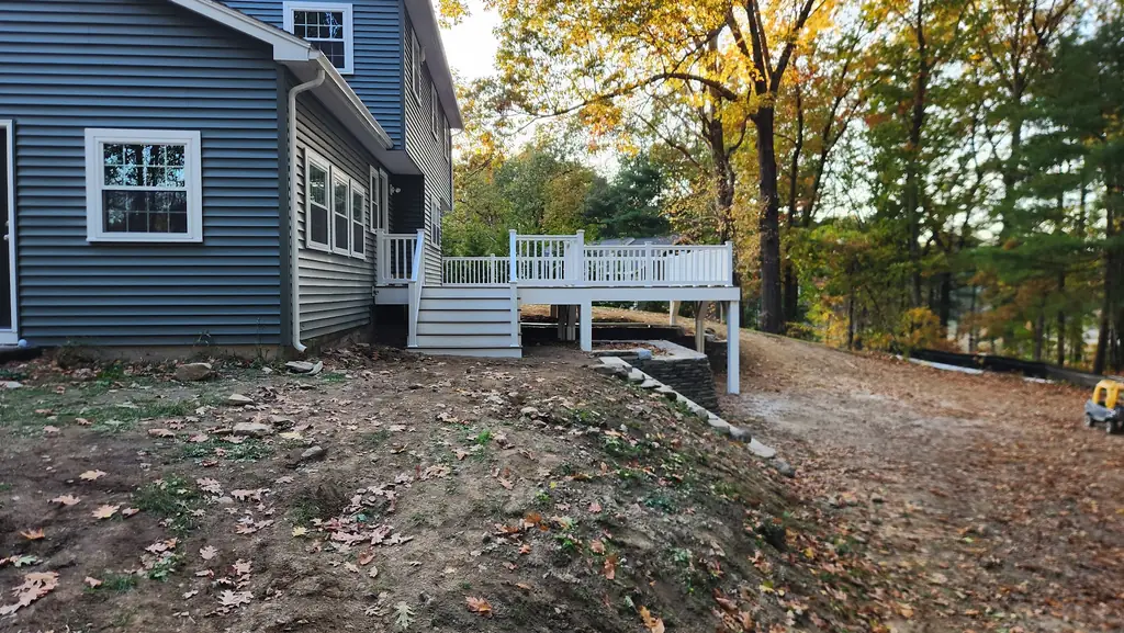 Rear of a house in new blue vinyl siding with a white deck, railing and steps