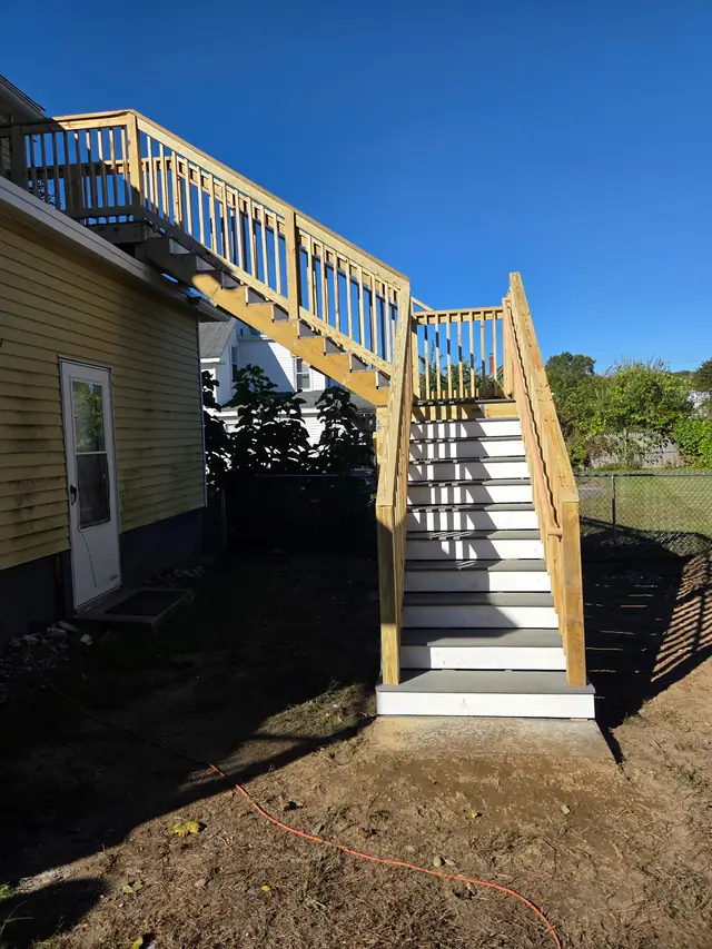 Pressure-treated stair run with white risers and a rail up to a second-storey door
